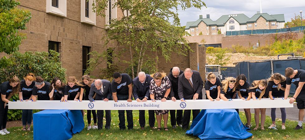 Students and faculty signing the beam