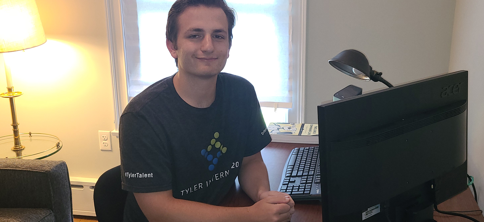 Photo of Michael O'Reilly sitting at a desk. O'Reilly is a computer science and cybersecurity major who is interning with Tyler Technologies this summer.