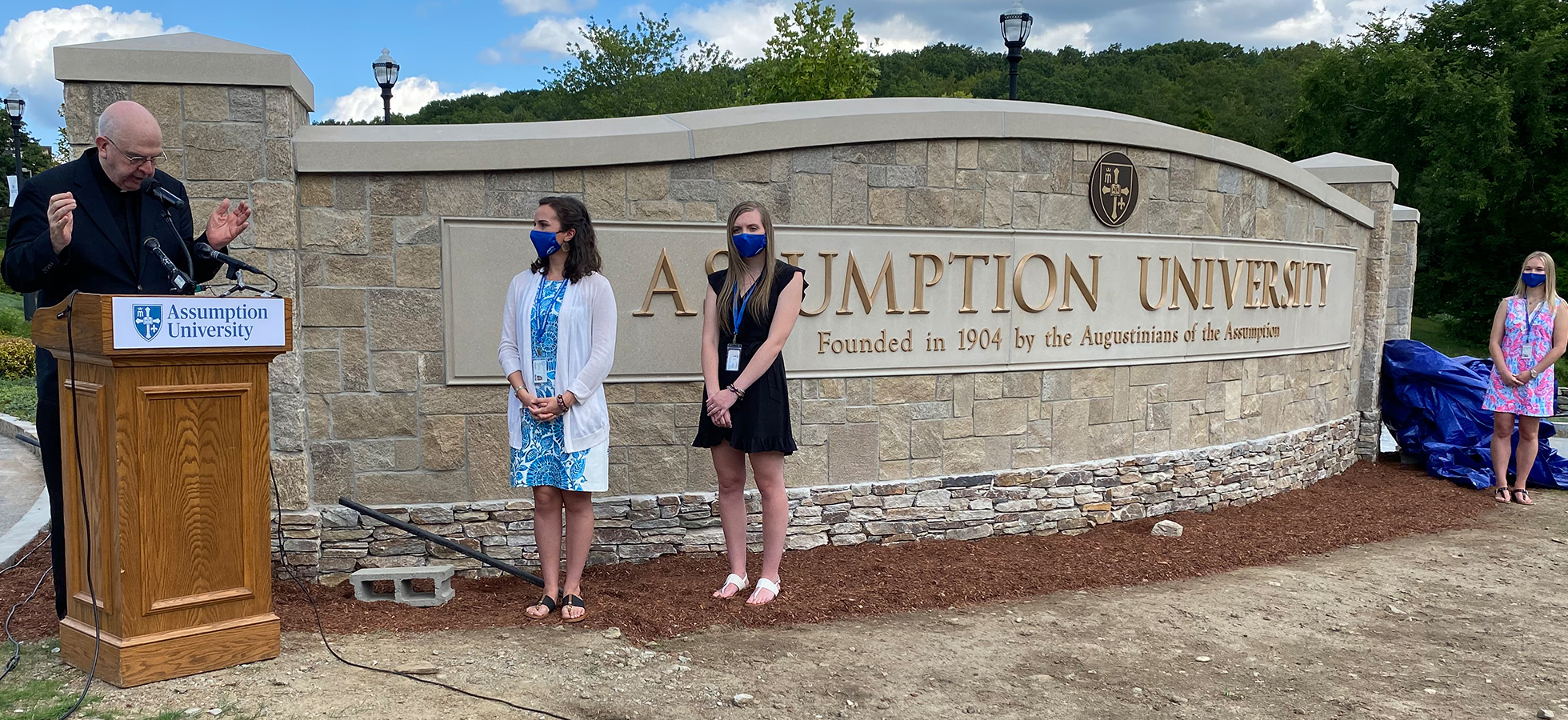Father Dennis Gallagher blessing the new Assumption University sign