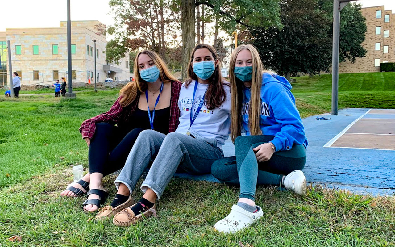Female students sitting outside with masks