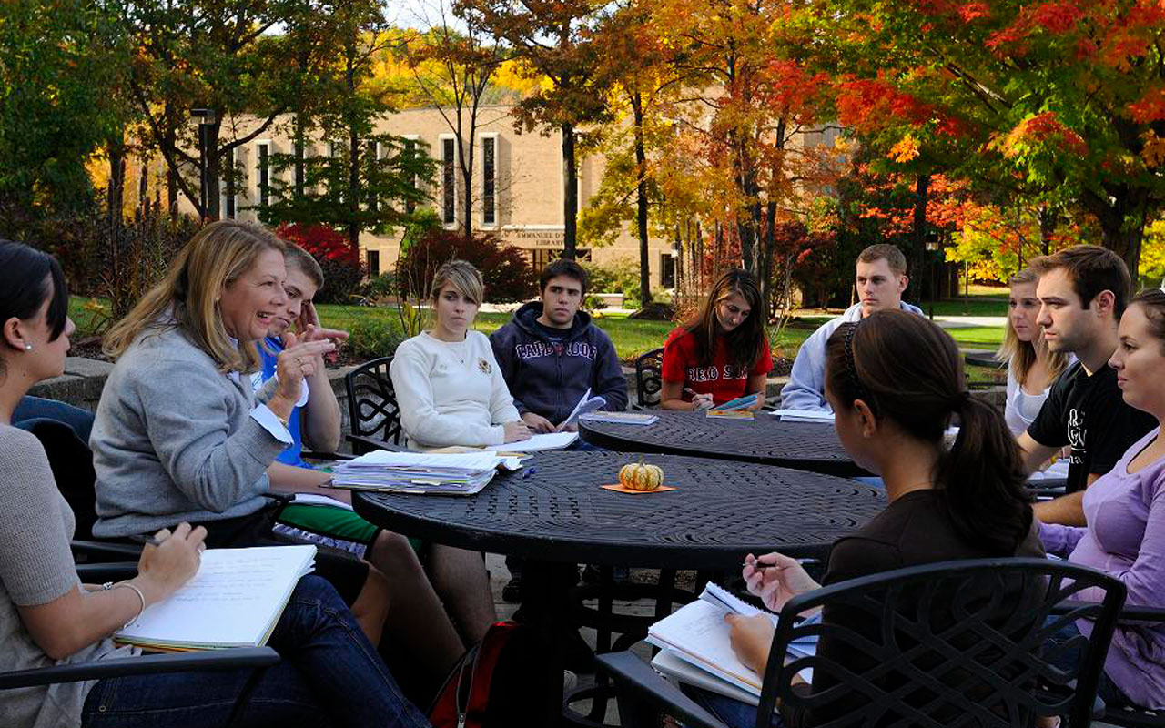 Students having class outside with fall foliage