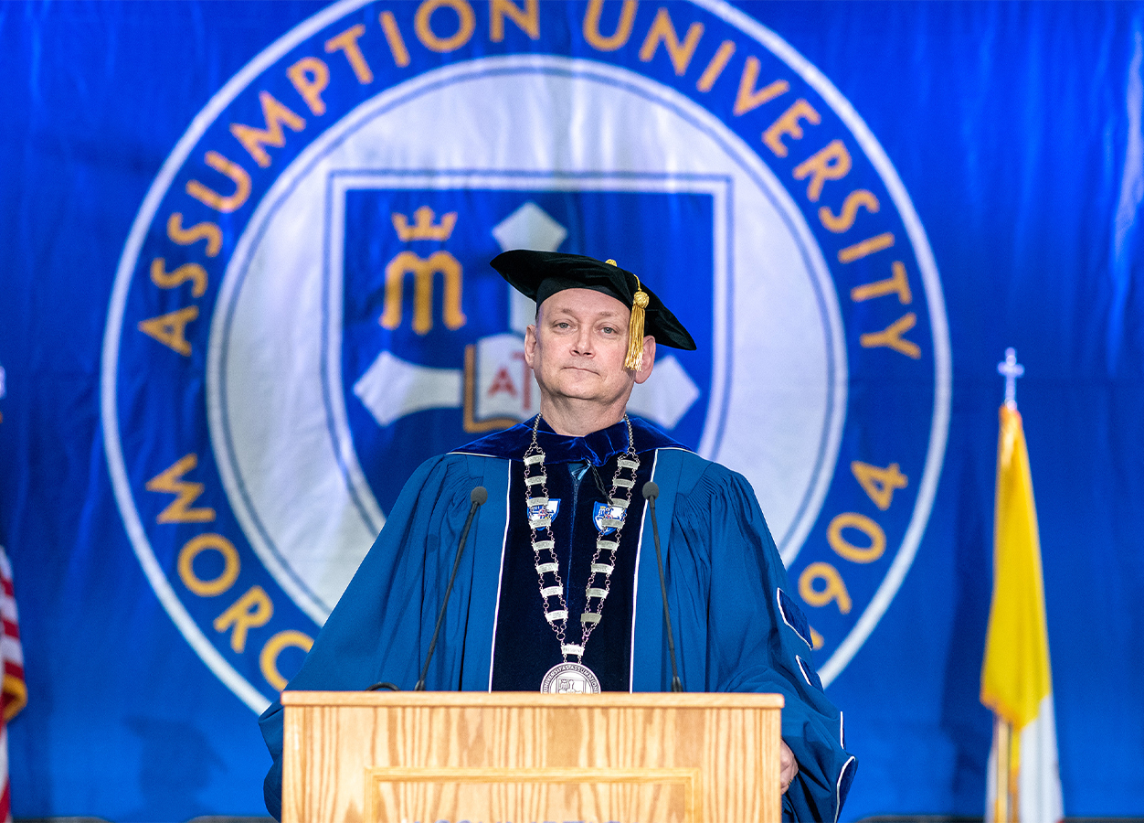 Dr. Greg Weiner at his inauguration ceremony on March 23, 2023 in front of a blue backdrop with the official Assumption University seal.