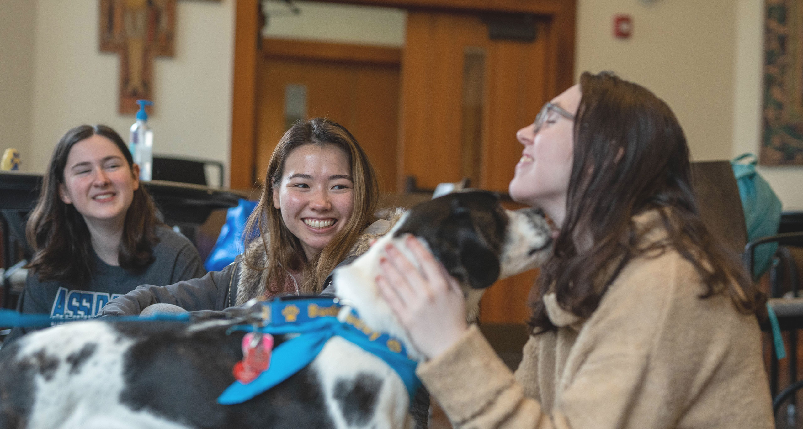 Assumption students petting a black and white dog