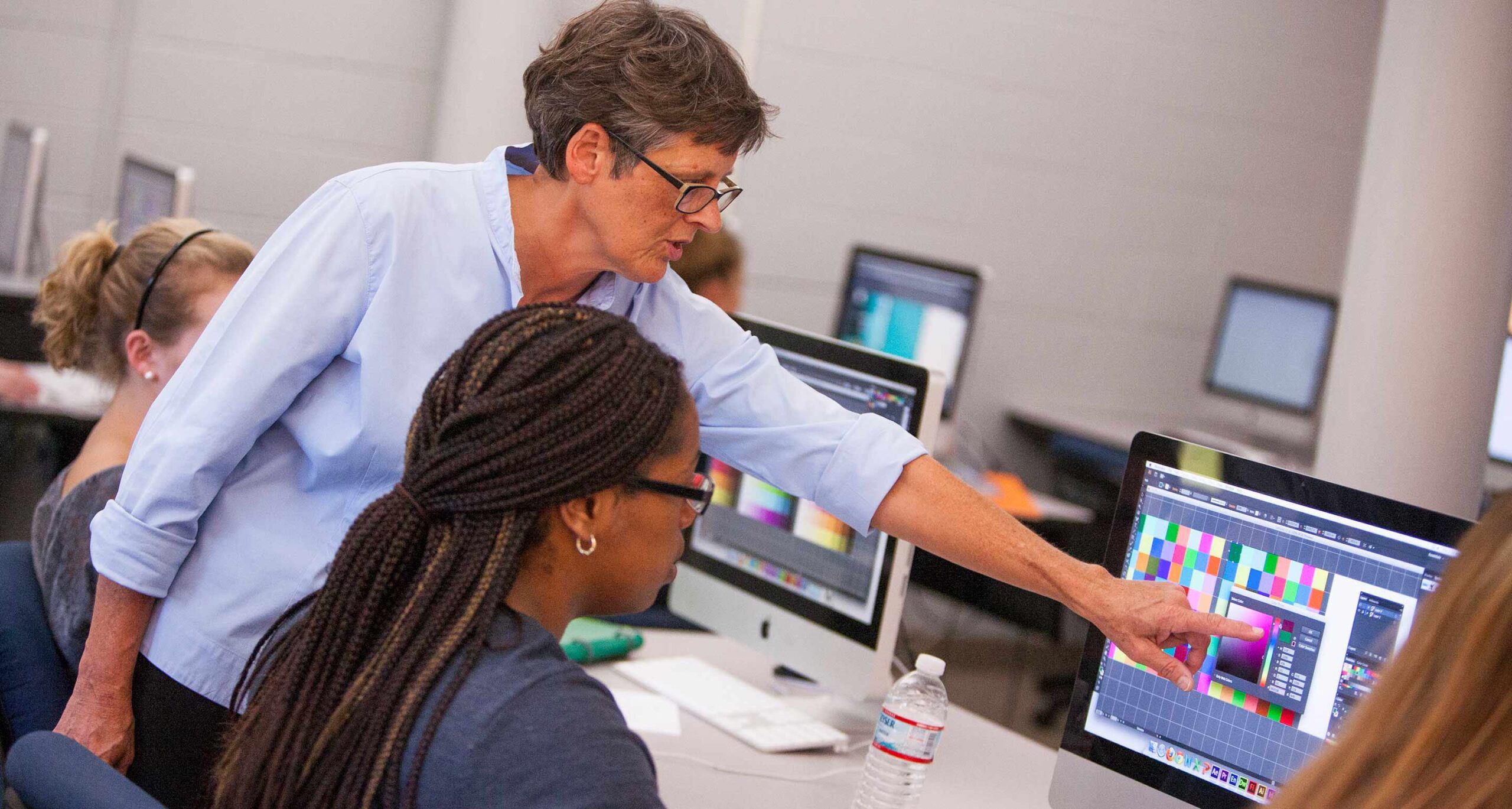 Graphic design faculty member at Assumption instructs a student on graphic design concepts
