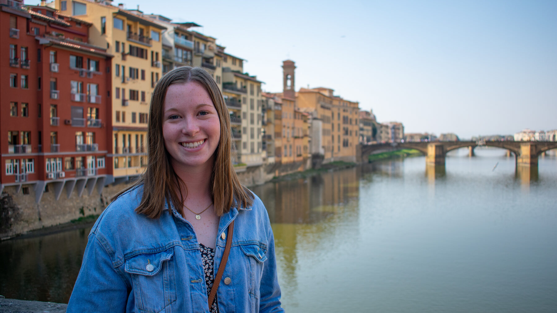 Student smiling at a study abroad location by a river. 