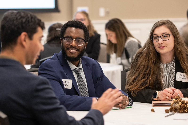 A male student male sitting at a table with a female student as they attend a networking night