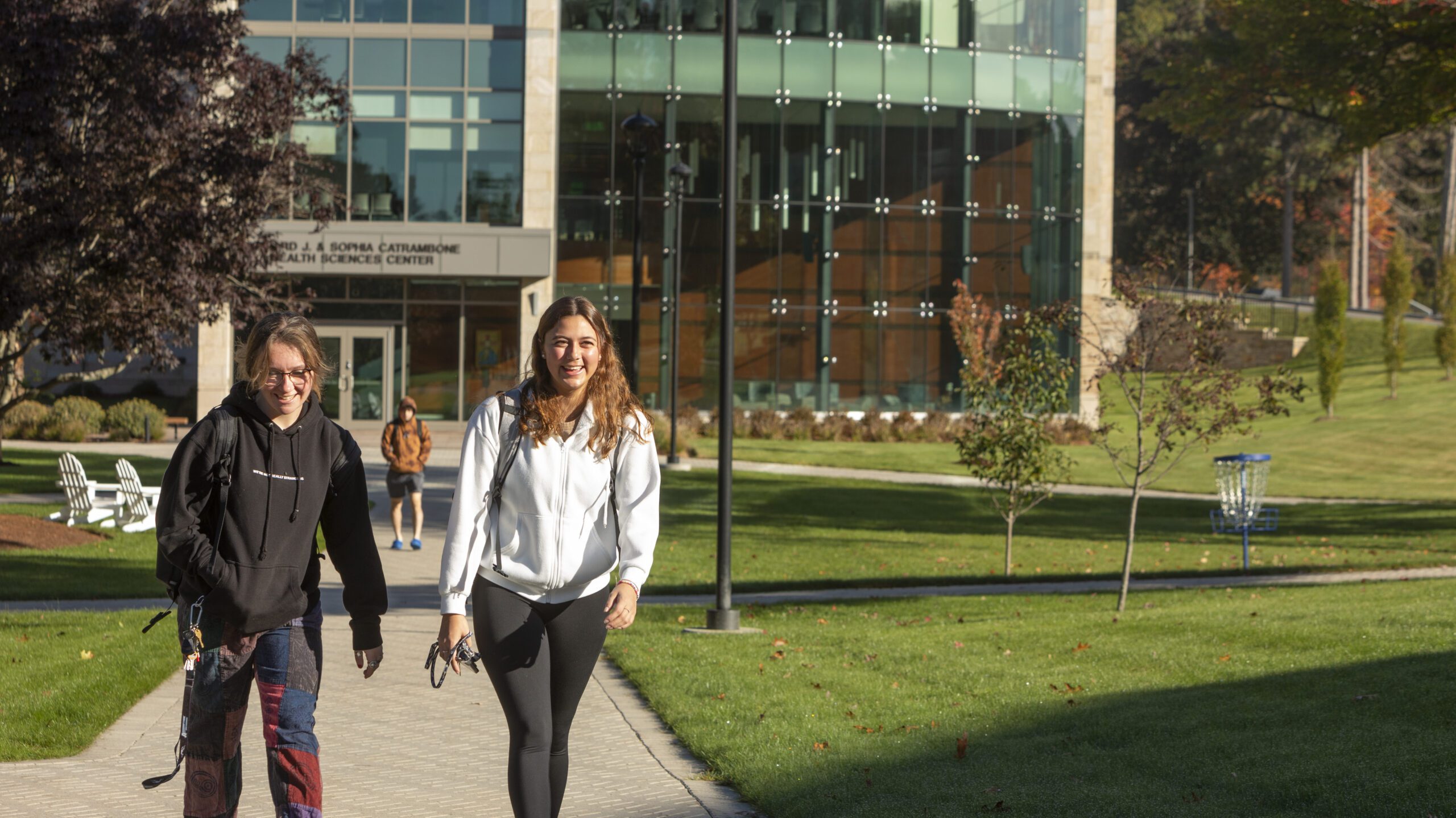 Two students walking outside by the Health Sciences building.