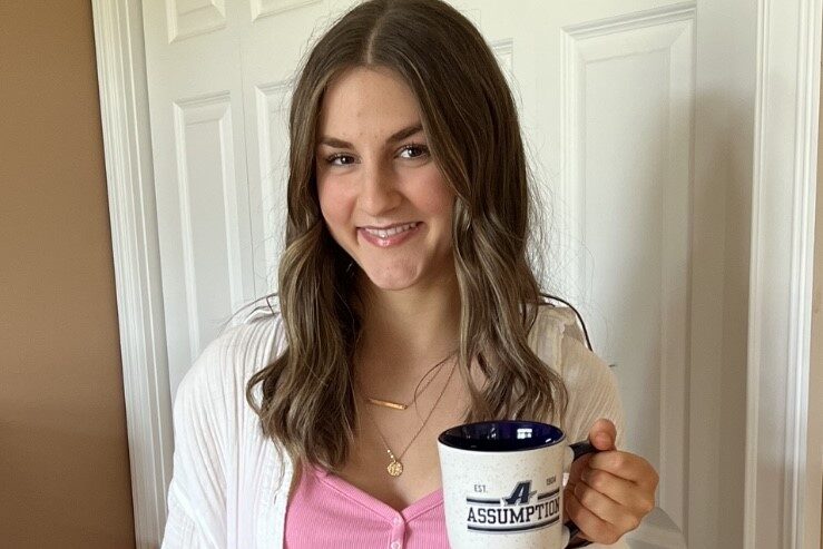 Assumption student Meredith Gendreau ’27 holding a coffee mug with the Assumption athletics logo on it