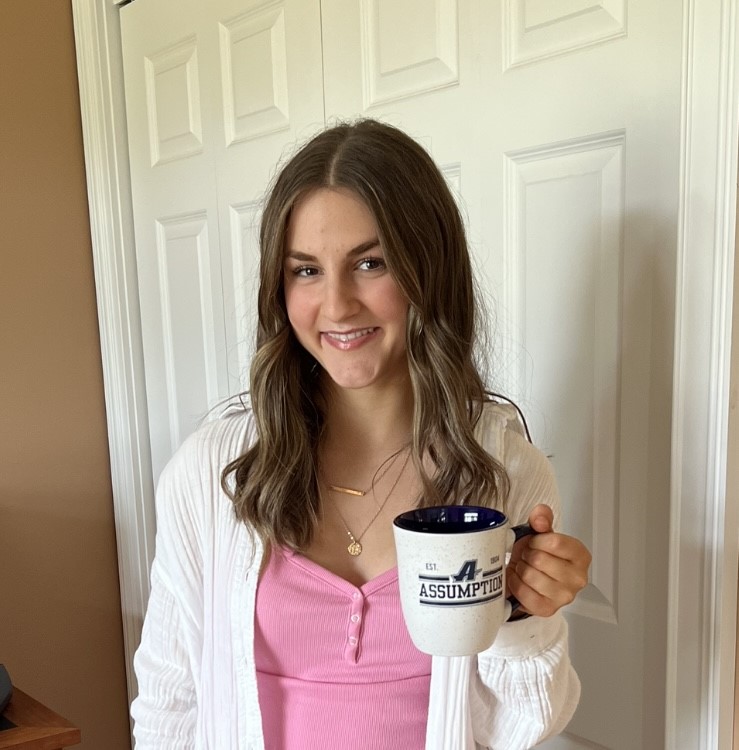 Assumption student Meredith Gendreau ’27 holding a coffee mug with the Assumption athletics logo on it