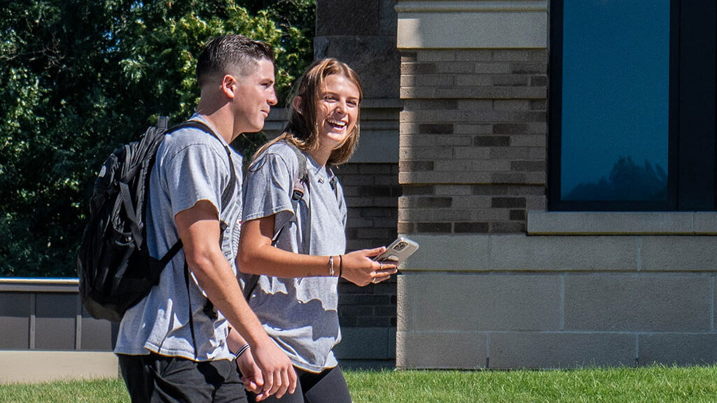 Two students walking outside talking to each other.
