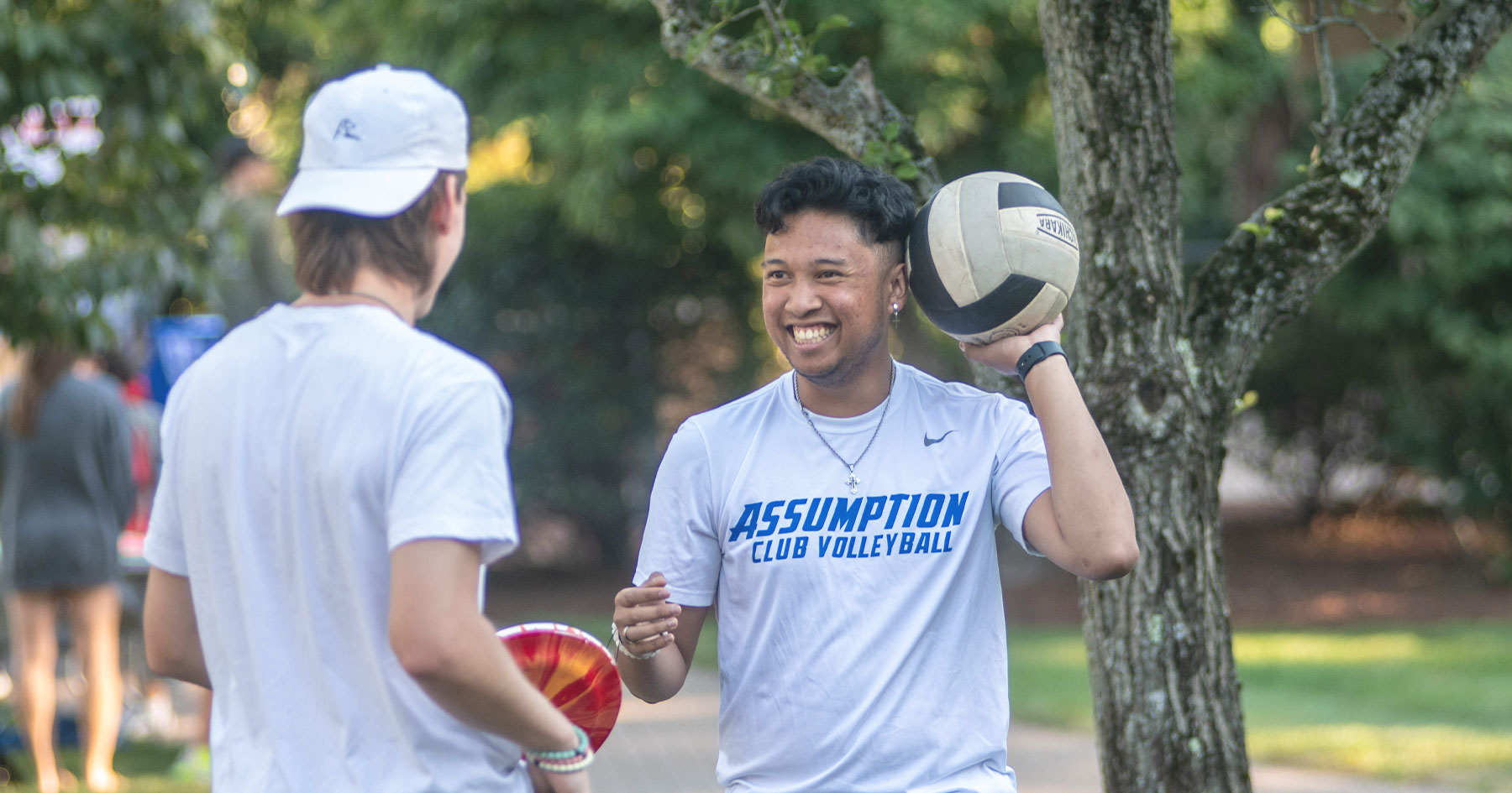 Assumption student holding a volleyball and wearing a shirt that reads 
