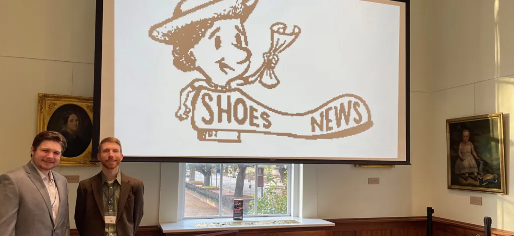 Adam Ide '24 and Professor John Bell at the SHOES Conference, with the logo.