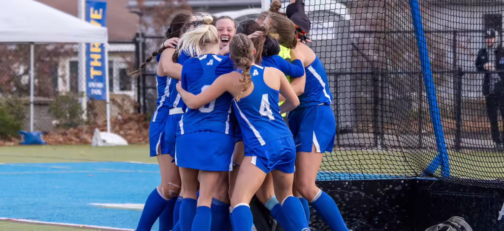 Members of Assumption's field hockey team celebrate their NE10 win.