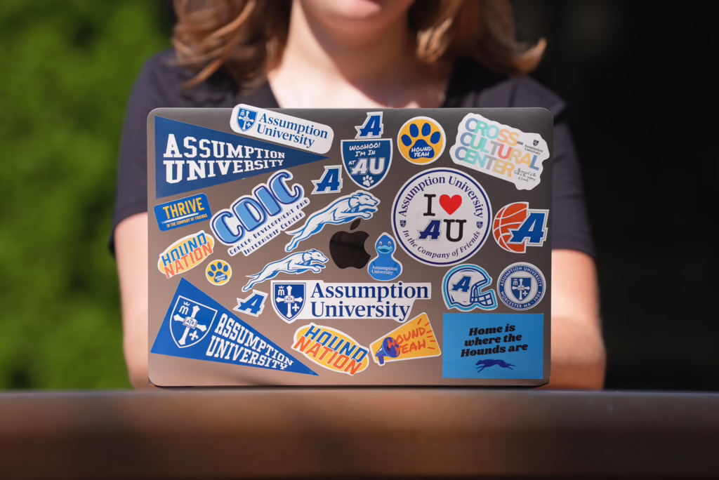 Image of an Assumption student working on a laptop with Assumption-branded stickers
