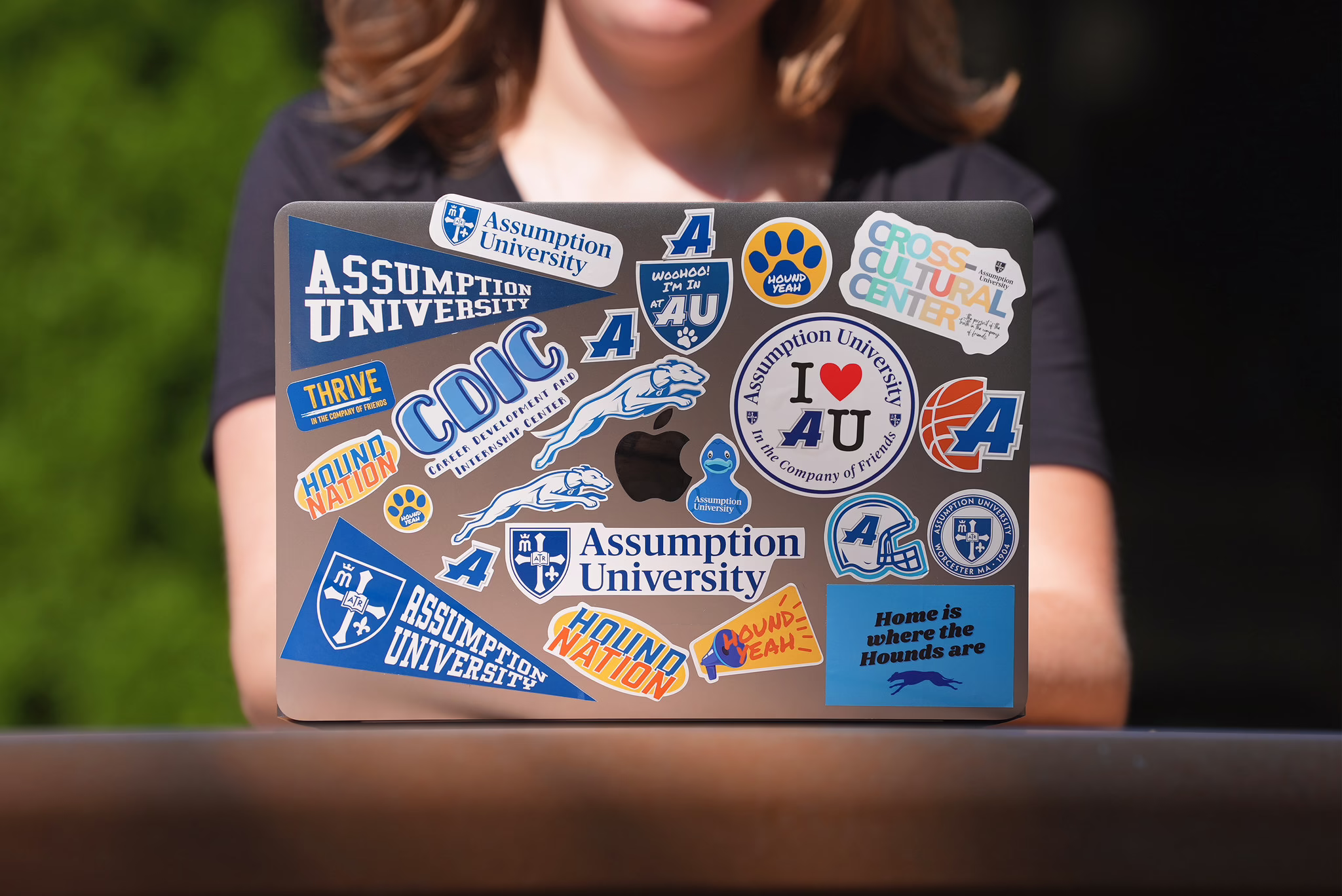 Image of an Assumption student working on a laptop with Assumption-branded stickers
